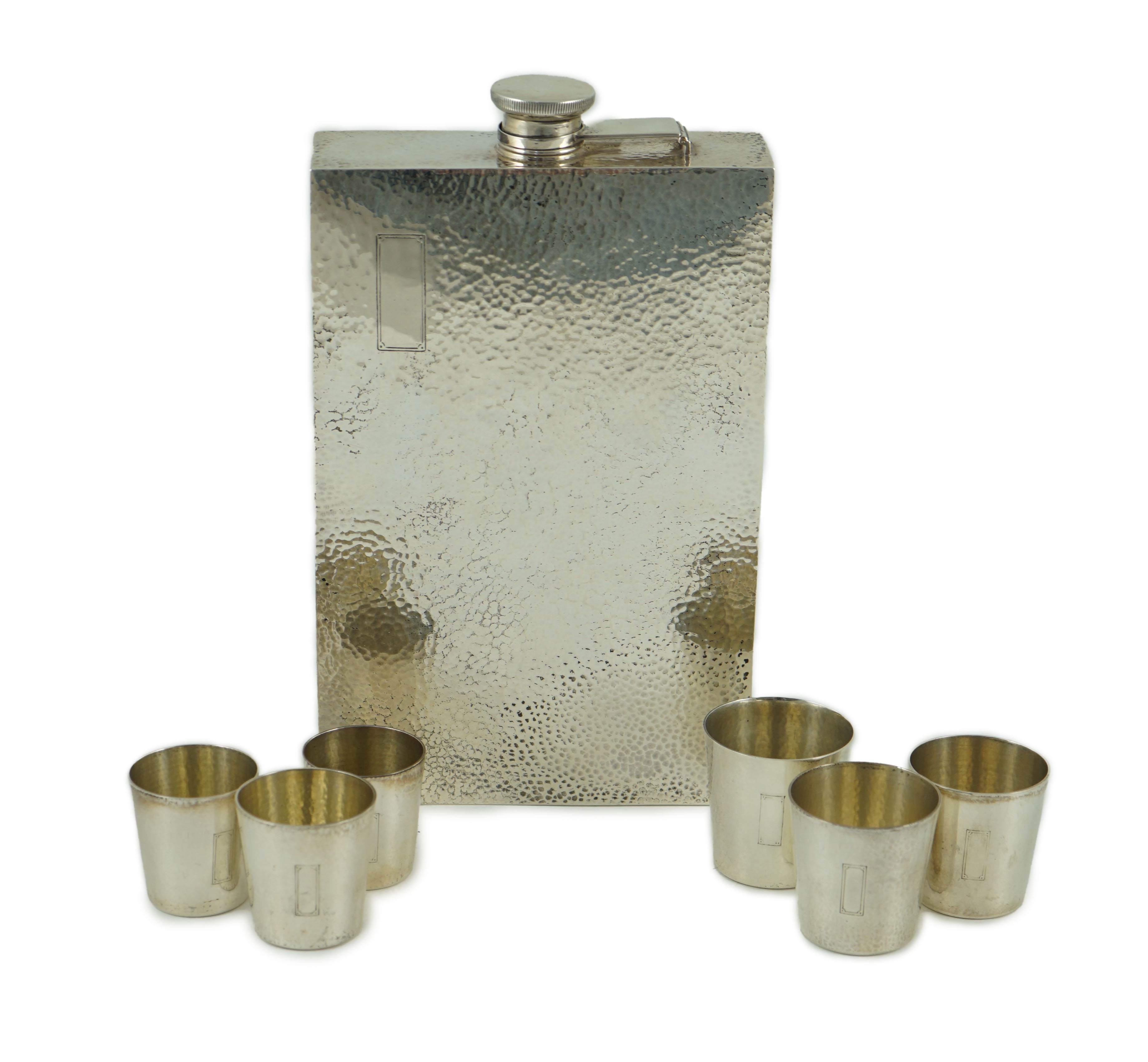 A 1930's/1940's planished sterling silver rectangular flask by Ahrendt & Kautzman, retailed by Cartier and six sterling similar graduated tots, signed Cartier